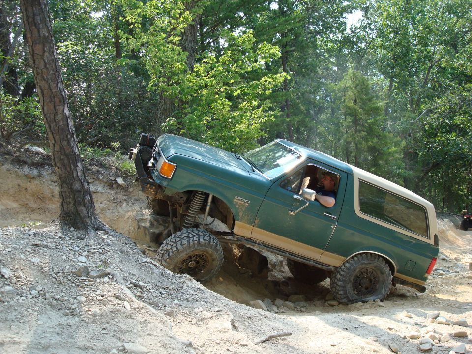 Green 1990 Ford Bronco climbing a rocky incline