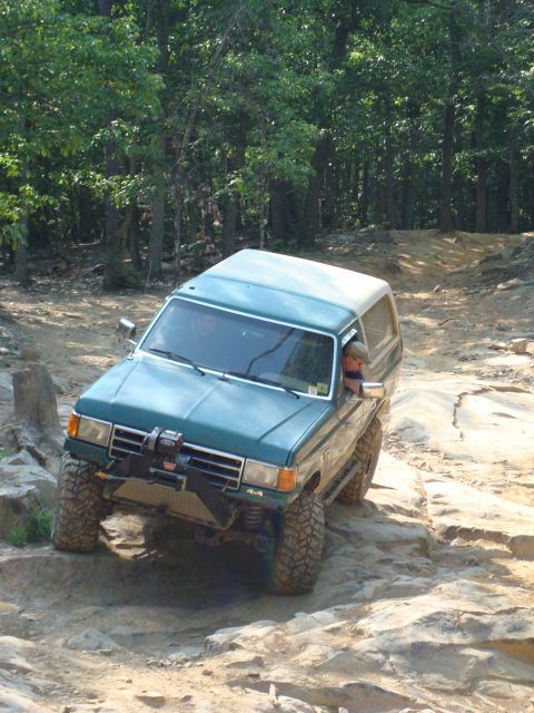 1990 Ford Bronco - This Ford Bronco navigates a rocky off-road trail, demonstrating its capability on challenging terrain.
