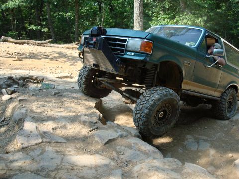 1990 Ford Bronco - This modified 1990 Ford Bronco tackles a challenging rocky trail with its impressive off-road capabilities.