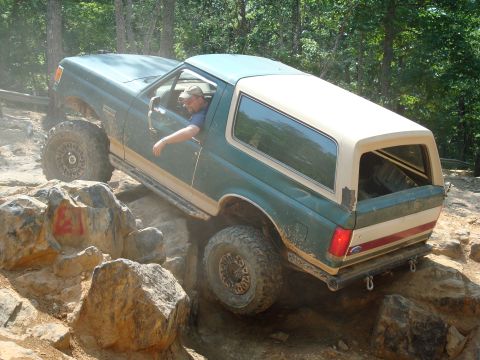 1990 Ford Bronco - Driver navigates a green 1990 Ford Bronco through a rocky off-road course.