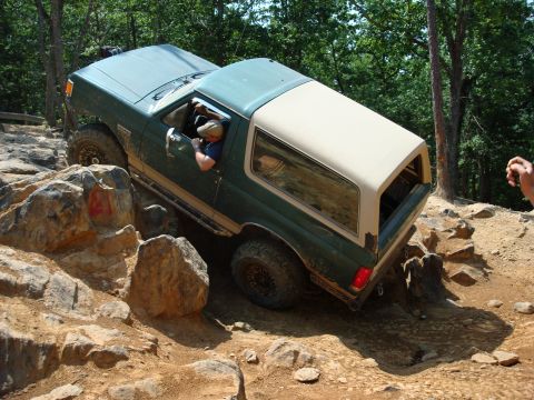 1990 Ford Bronco - A 1990 Ford Bronco tackles a challenging off-road course with large rocks and steep inclines.