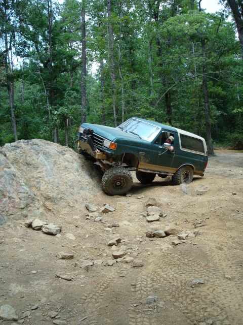 1990 Ford Bronco - This green Ford Bronco navigates a challenging rocky terrain, demonstrating its off-road capabilities.