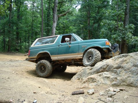1990 Ford Bronco - Green 1990 Ford Bronco navigating a rocky off-road course.