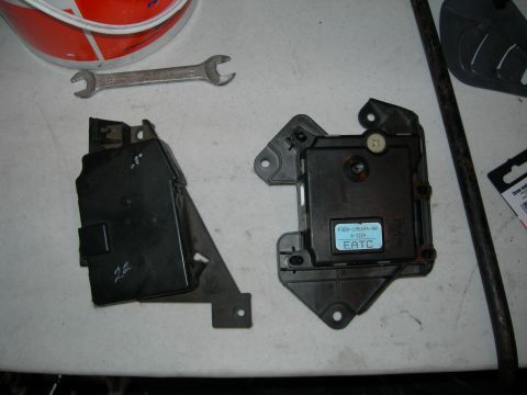 1992 Ford Taurus - Two black plastic HVAC blend-door actuator/control modules laid on a white workbench, the right one labeled "EATC" with Ford part number F3…