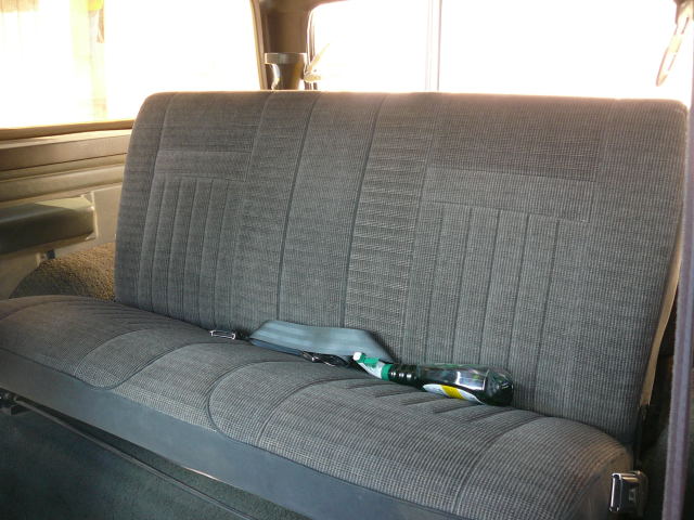 Back seat of a vehicle with a seatbelt and a bottle on it