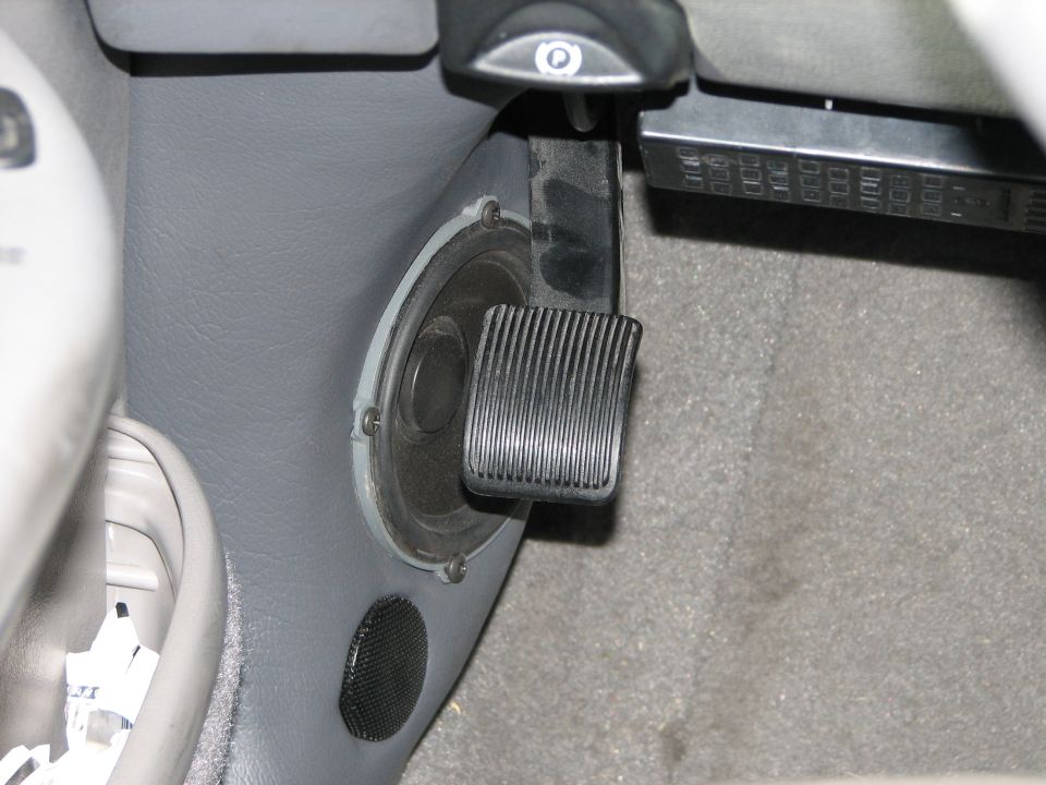Gray interior kick panel with a speaker and brake pedal visible