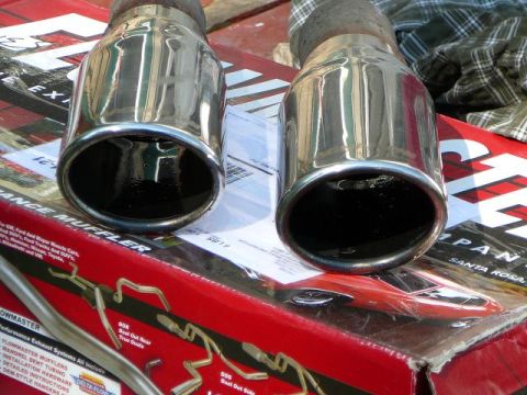 1997 Mercury Grand Marquis - Close-up of two shiny exhaust tips on top of a box containing performance exhaust system parts.