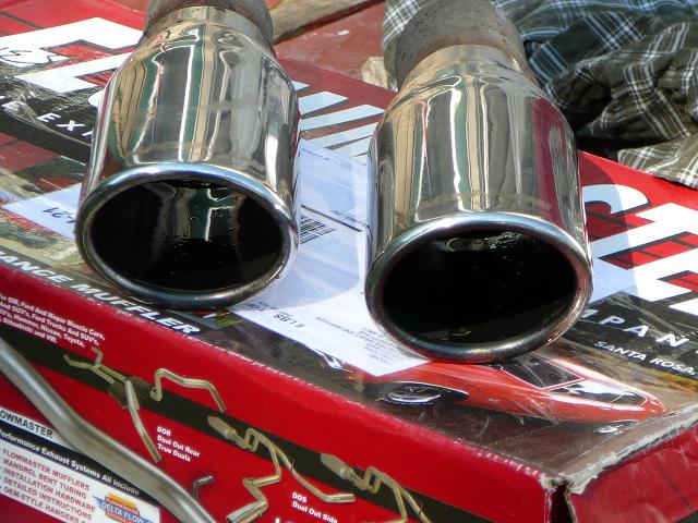 two chrome exhaust tips resting on a red box with car parts diagrams