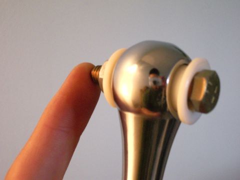 1995 Ford Probe - A finger holds a bolt with washers on a shiny metal car part, likely for installation.