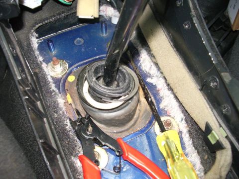 1995 Ford Probe - Tools are laid out next to the exposed gear shifter mechanism in a vehicle's interior.