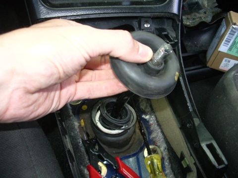 1995 Ford Probe - A hand removes a rubber boot from the shifter area of a car's center console.