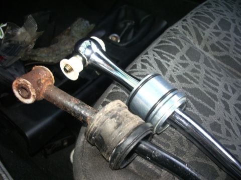 1995 Ford Probe - Comparison of a worn-out shifter linkage and a new replacement part, likely for a manual transmission vehicle.