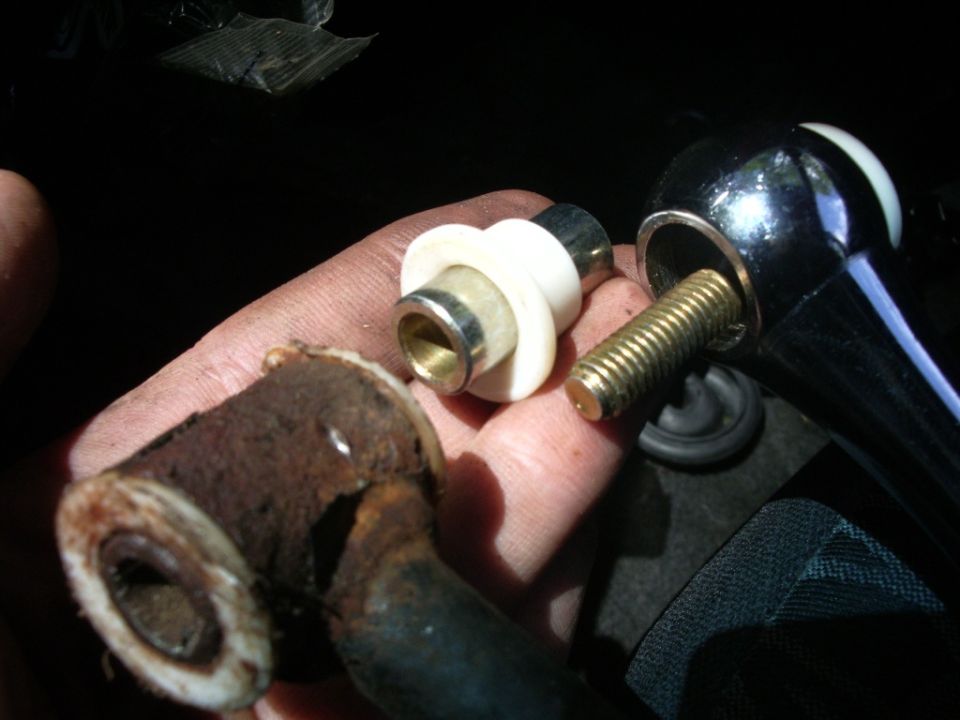 Hand holding rusty metal car part and chrome shifter with brass bolt