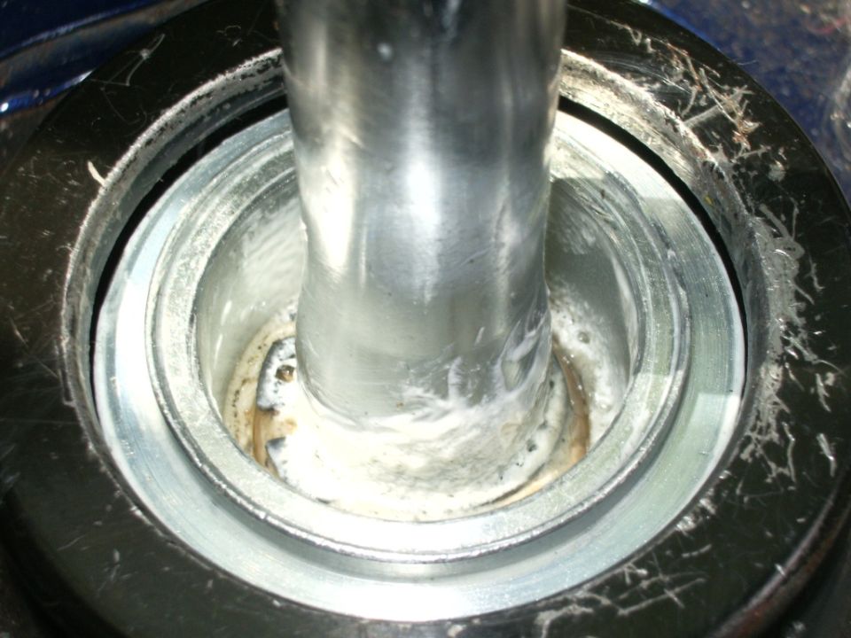 Close-up of a metal shifter shaft inside a housing with white grease
