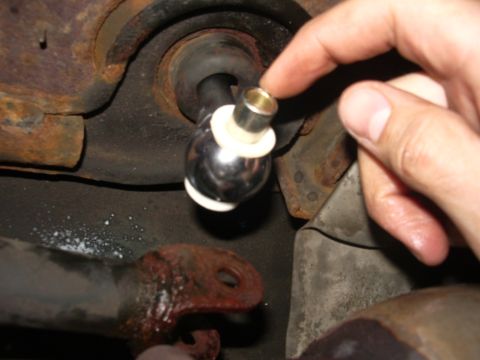 1995 Ford Probe - A person is installing a shiny ball joint with white plastic washers into a rusty car suspension component.