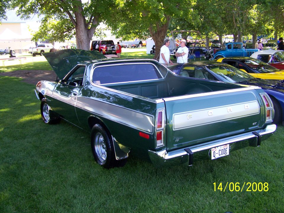Green 1972 Ford Ranchero with hood up, parked on grass at an outdoor car show