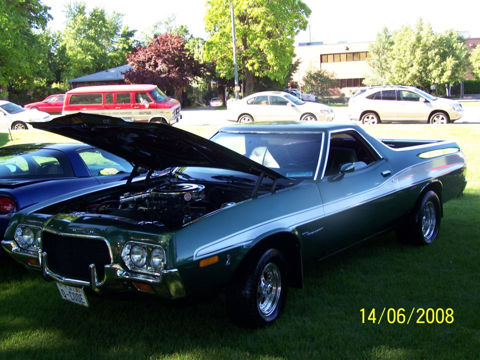 Green 1970s pickup truck with hood open, showing engine. White stripe along side