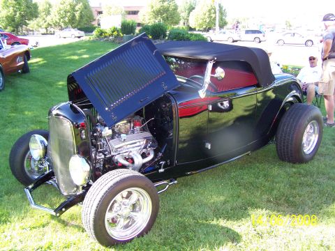 1972 Ford Ranchero - A black convertible hot rod is displayed with its hood open, revealing the engine and a glimpse of its red interior.