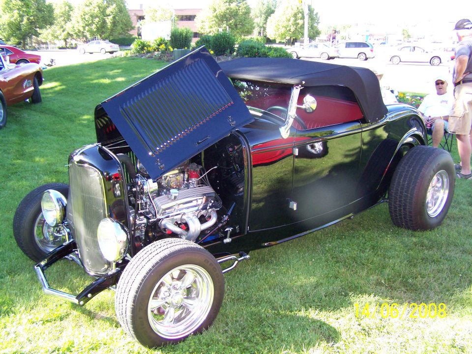 Black convertible hot rod, hood open, red interior, chrome grille and wheels
