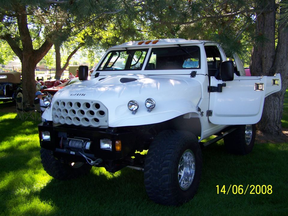 White custom truck with a large grille, open driver's door, and winch