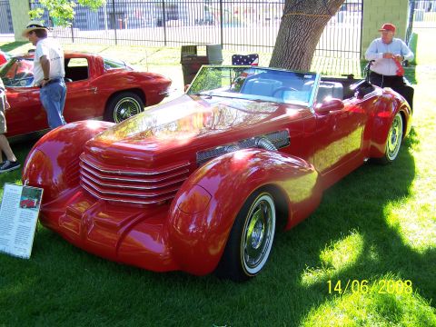 1972 Ford Ranchero - A striking red convertible with a distinctive grille and visible engine components is displayed on a grassy lawn.