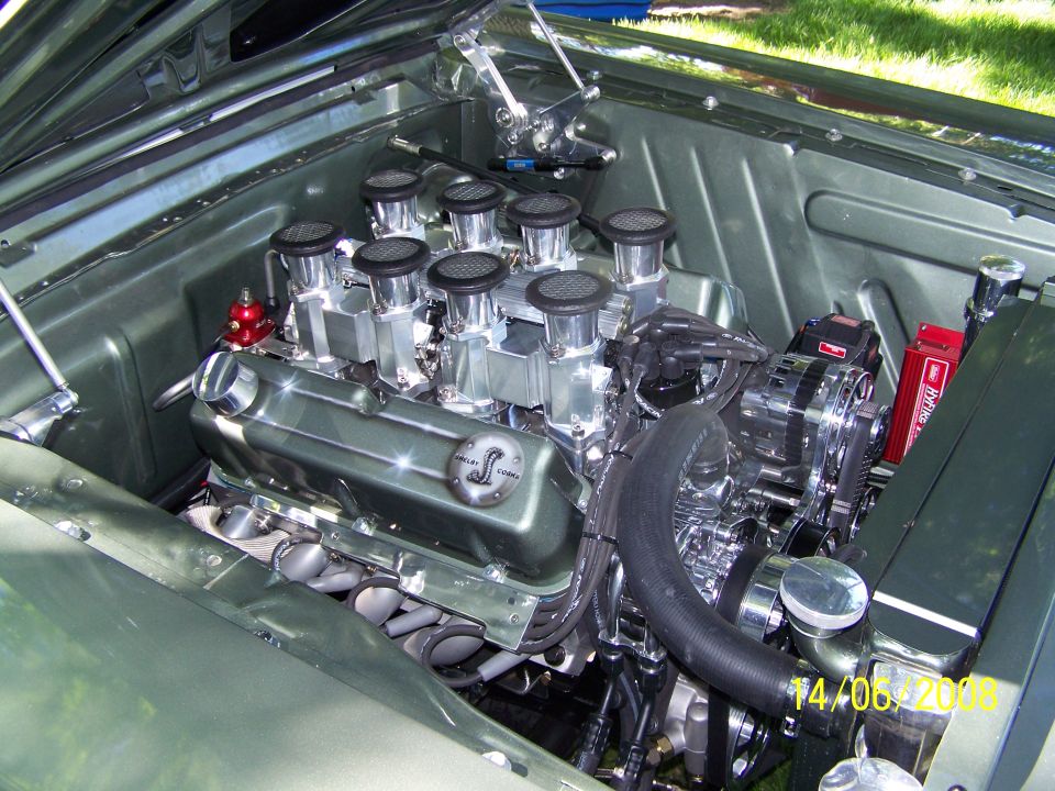 Close-up of a V8 engine with eight individual carburetors and a Shelby Cobra valve cover