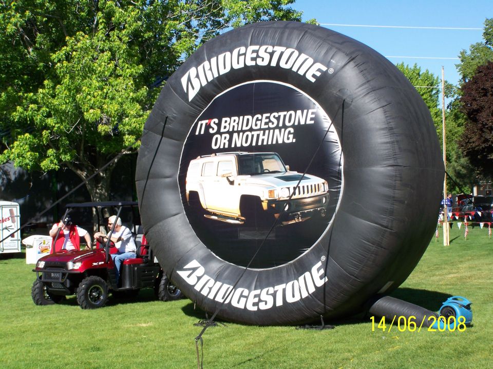 Giant inflatable Bridgestone tire with a Hummer image inside. A red golf cart is nearby