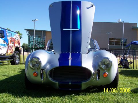 1972 Ford Ranchero - Front view of a silver Shelby Cobra replica with blue racing stripes, hood open, parked on grass.