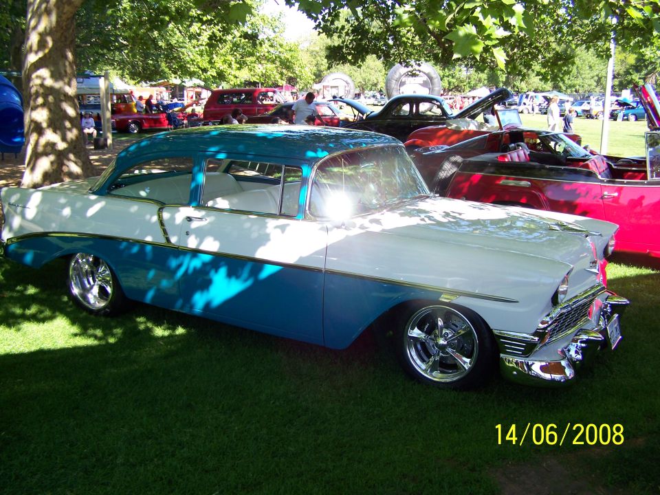 Two-tone blue and white sedan with chrome wheels parked on grass