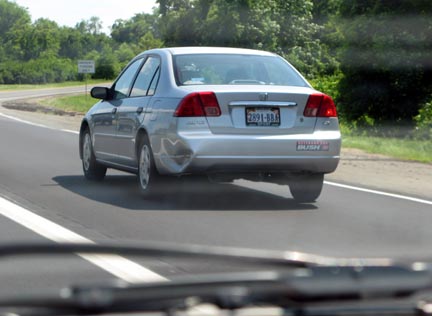 1971 Ford Ranchero - A silver sedan is seen from behind on a highway, with a dent on its rear passenger side.