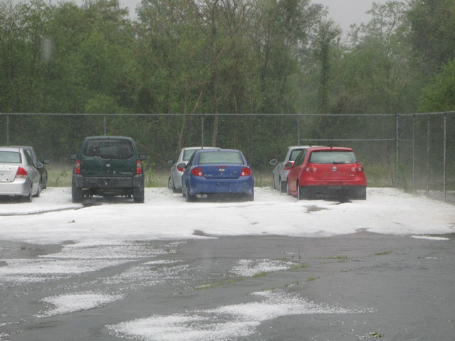 Several cars parked in a lot covered in hail