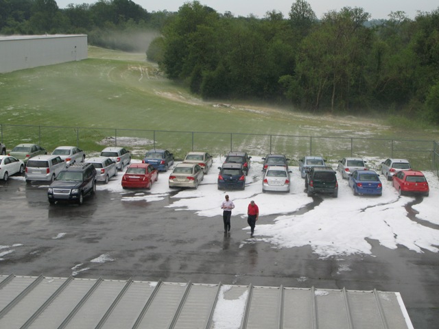 Cars in a parking lot covered in hail, with two people walking