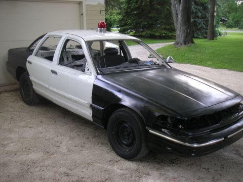 1997 Ford Crown Victoria - This two-tone 1997 Ford Crown Victoria police car is in a state of disrepair, with missing doors and trim.