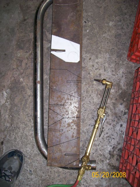 1984 Ford Bronco - Metal part marked for cutting, with a torch and template nearby.