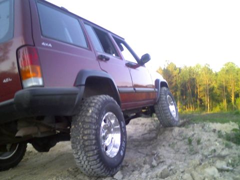 1998 Jeep Cherokee - A maroon Jeep Cherokee is shown flexing its suspension on a dirt incline.