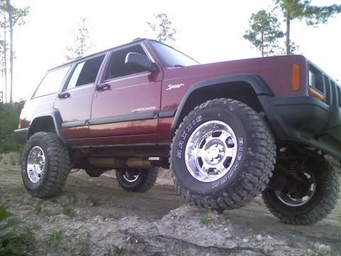 1998 Jeep Cherokee - A maroon 1998 Jeep Cherokee Sport is shown with its front wheel elevated on an obstacle.