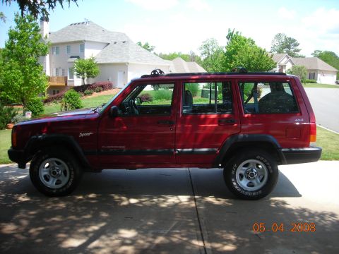1998 Jeep Cherokee - A red 1998 Jeep Cherokee Sport is parked in a driveway on a sunny day.