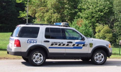 1991 Ford Crown Victoria - A silver SUV with "LINCOLN POLICE" markings and an emergency light bar is parked on the side of the road.
