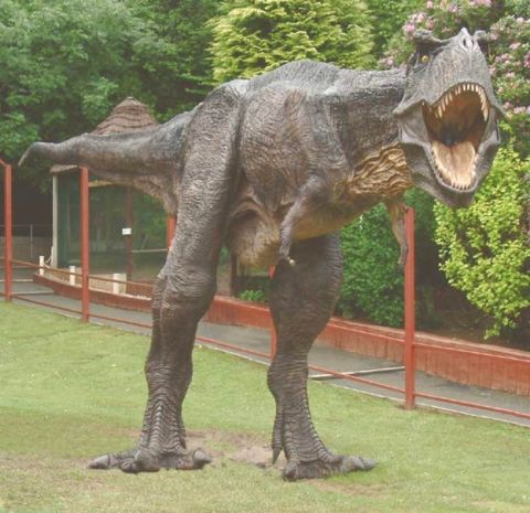 1991 Ford Crown Victoria - A realistic dinosaur model is displayed outdoors in a grassy area with foliage in the background.