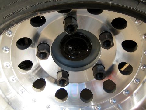 1996 Ford Bronco - A detailed view of a vehicle's wheel hub assembly, showing the lug nuts and tire sidewall markings.