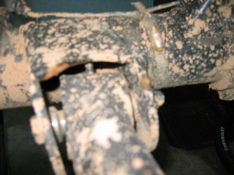 1992 Ford Mustang - A close-up view of a vehicle's suspension component heavily coated in mud.