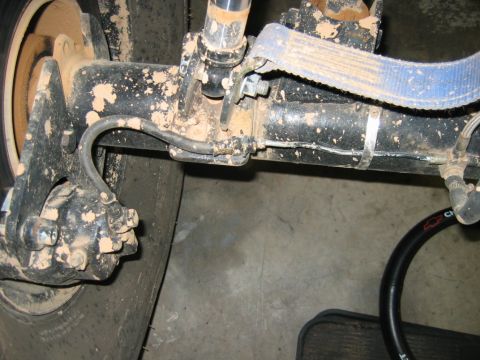 1992 Ford Mustang - Close-up view of muddy rear axle and suspension parts, showing brake components and a leaf spring.