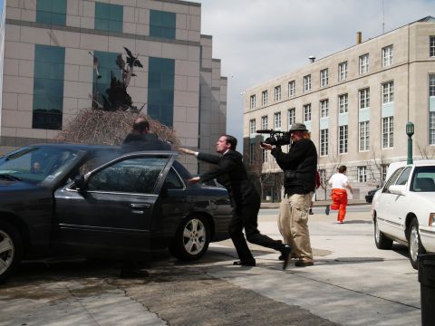 1985 Ford LTD Crown Victoria - A film crew captures a dramatic scene involving a dark sedan and actors on a city street.