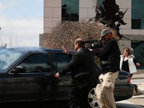 1985 Ford LTD Crown Victoria - A black sedan is filmed by a cameraman as a man opens the car door, with a woman in the background.