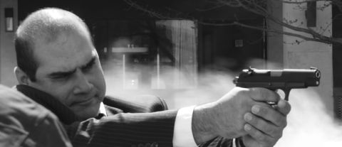1985 Ford LTD Crown Victoria - A man in a suit is aiming a pistol with smoke in the background.