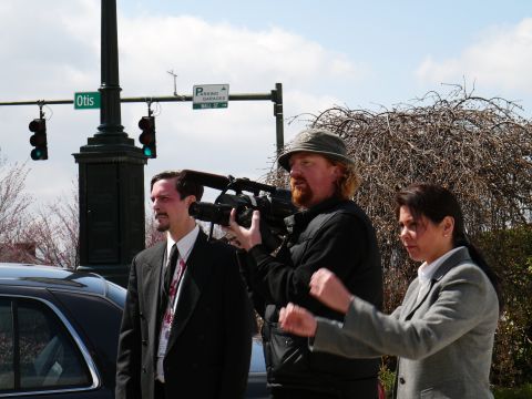 1985 Ford LTD Crown Victoria - A film crew is at work on a street corner, with a cameraman filming a man in-suit man.