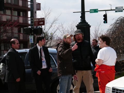 1985 Ford LTD Crown Victoria - People gather on a street corner with a black car and street signs visible.