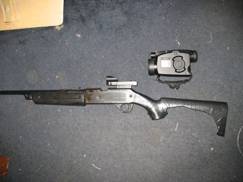 1997 Ford Crown Victoria - A shotgun with attached optics and a night vision device is displayed on a carpeted surface.