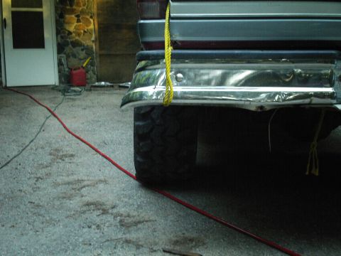 1994 Ford F-150 - The rear of a vehicle is shown, focusing on the bumper and tire, with a red cord on the ground.