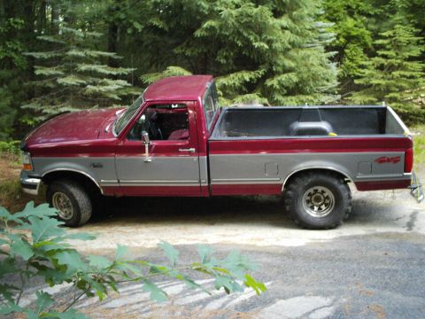 1994 Ford F-150 - This two-tone maroon and grey 1994 Ford F-150 pickup truck is shown from the side.